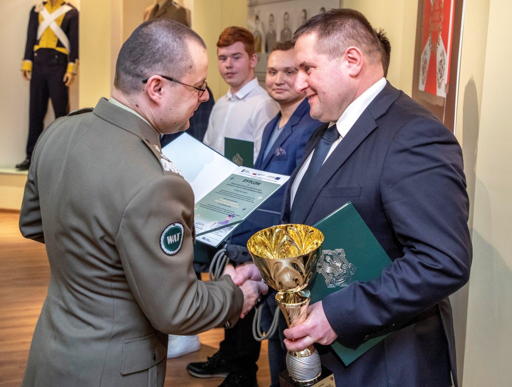 „Rektor-Komendant WAT, gen. bryg. prof. dr hab. inż. Przemysław Wachulak wręczający nagrodę opiekunowi naukowemu zespołu, który zajął II miejsce w konkursie, panu Mariuszowi Pawlakowi”